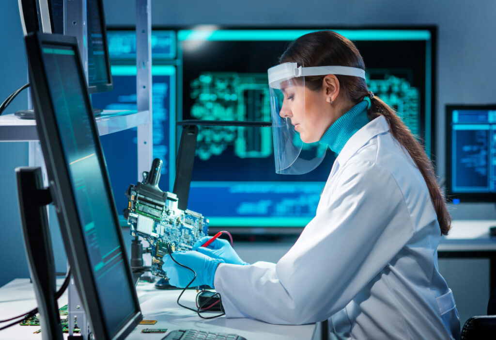 Workplace of young woman in modern microelectronics manufacturing lab. Engineer works in a modern scientific laboratory on computing systems and microprocessors. Futuristic concept.